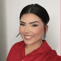 Elissiya, Red Fox Electric Customer Service Representative, Smiling In Red Company Uniform Against Neutral Background.